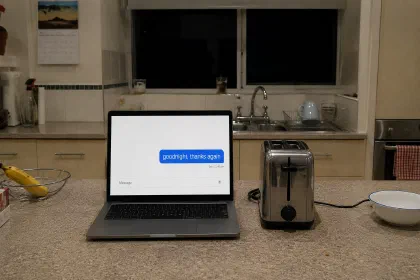 A laptop on a kitchen bench at night, next to a toaster. On screen, a single sent message: “goodnight, thanks again”, at 11:48 pm.